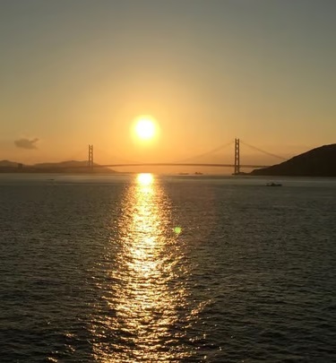 Sunset over the water with a suspension bridge on the horizon