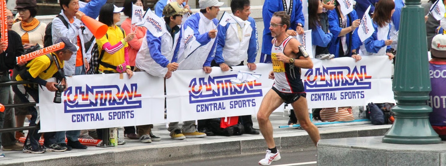 Scott racing the Osaka Marathon alongside spectators cheering behind barriers